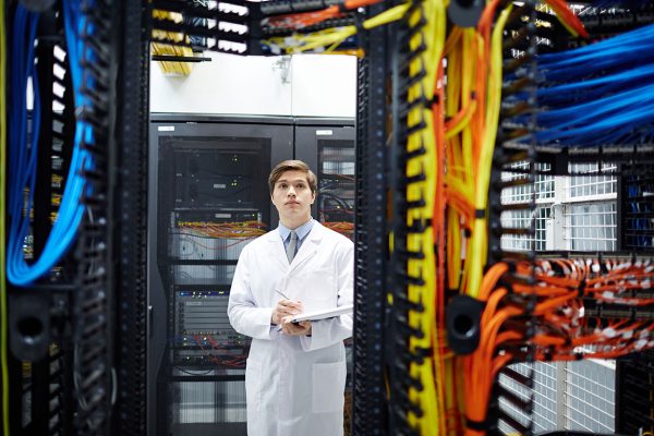 Serious programmer in whitecoat carrying out check-up of new hardware in mining farm
